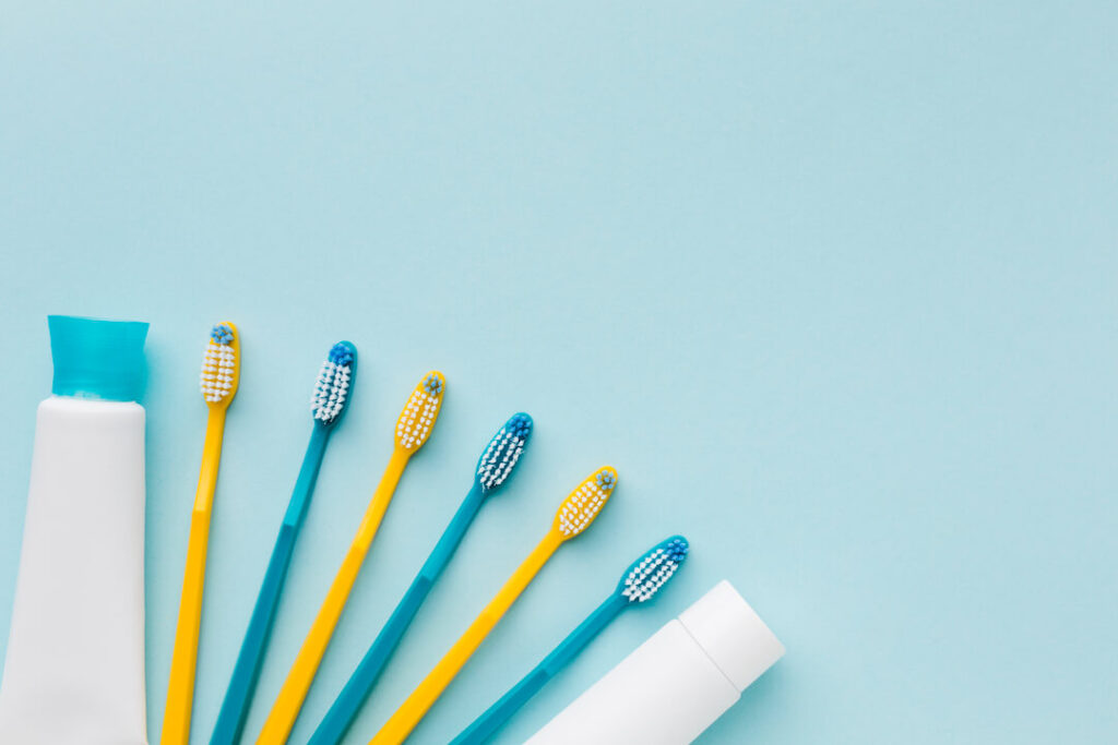 foto de cepillos de dientes amarillos y turquesas y pasta dental sobre fondo color aguamarina